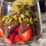Homemade Dubai chocolate strawberries in a clear layered dessert glass