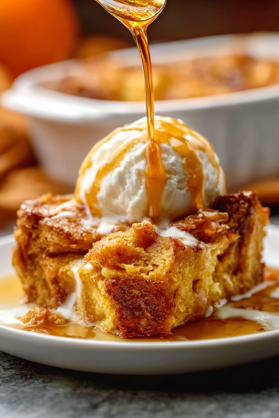 Pumpkin Bread Pudding with glaze in a white dish, drizzled vanilla glaze