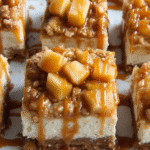 caramel apple cheesecake bars on tray with caramel drizzle