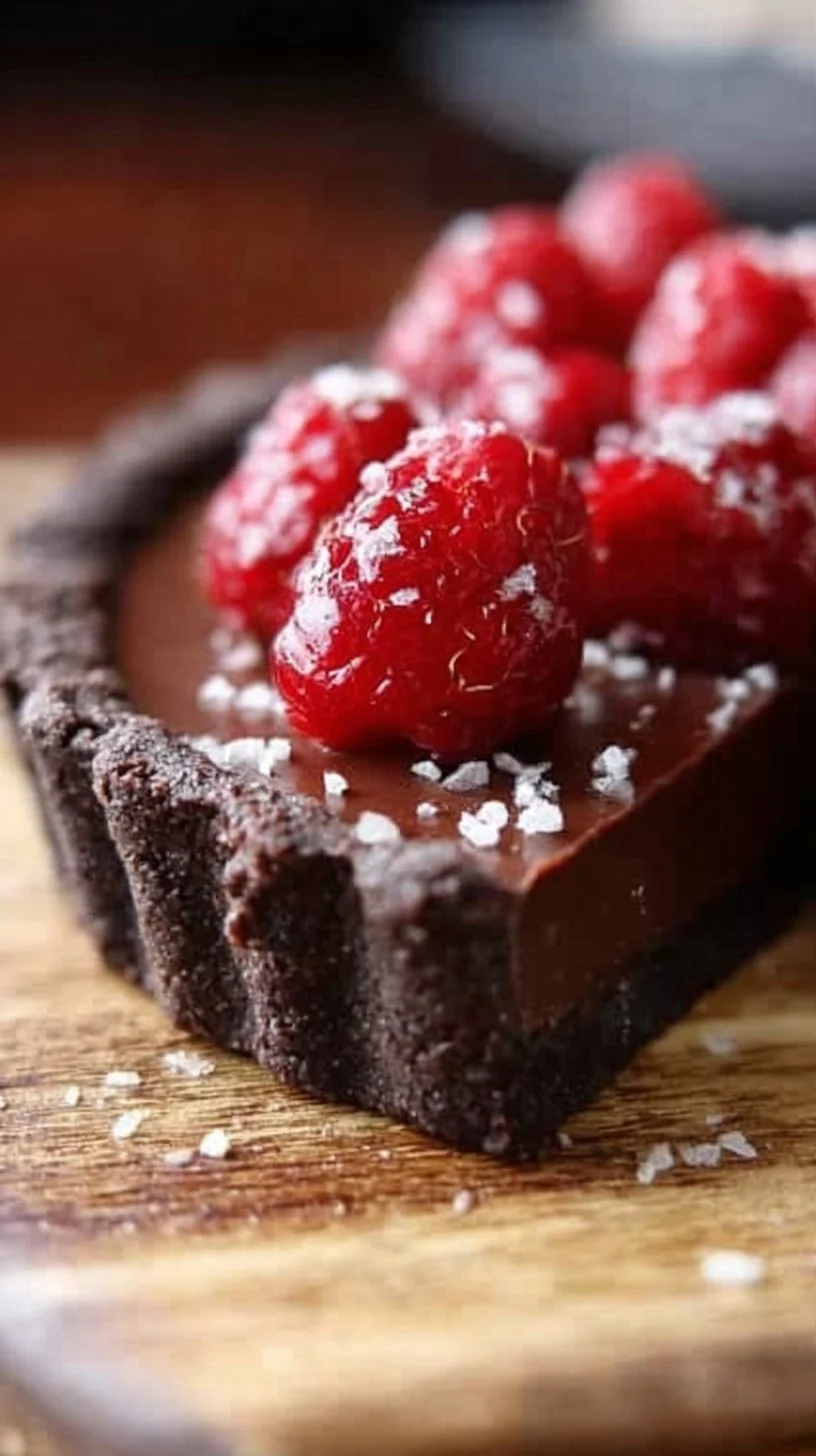 A decadent Chocolate Raspberry Tart decorated with fresh raspberries and chocolate curls